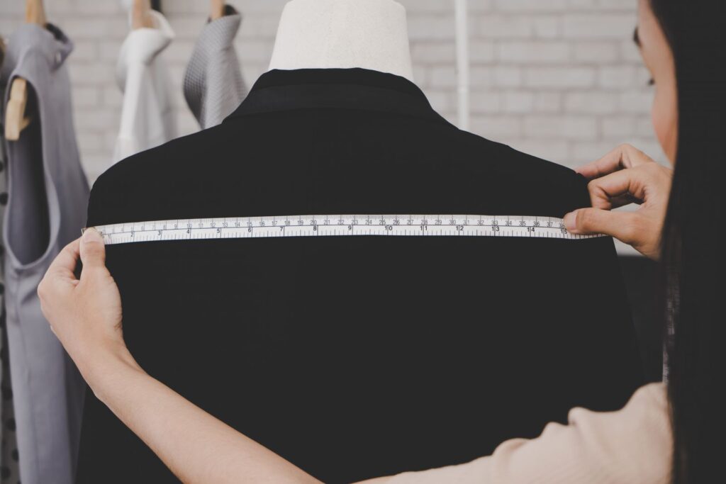 Woman measuring width of mannequins' shoulders.