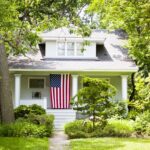 A house that is white with an American flag on the porch.