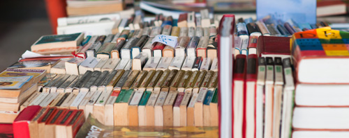 Used books arranged on a table, spines facing upward.