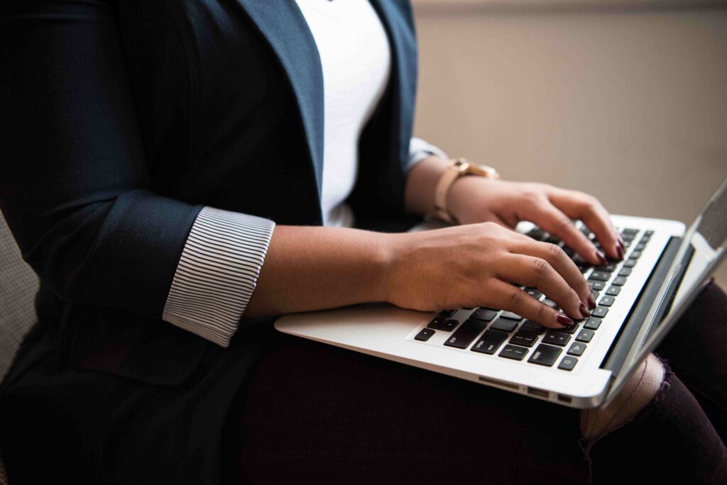 A woman's hands are resting on a laptop keyboard.