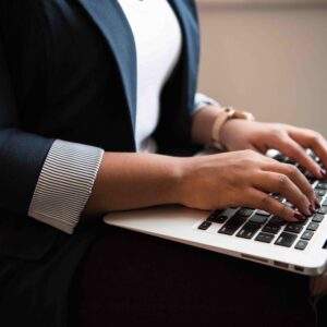 A woman's hands are resting on a laptop keyboard.