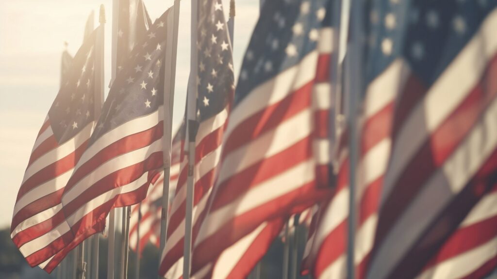 A close up of a group of American Flags in faded sunlight.