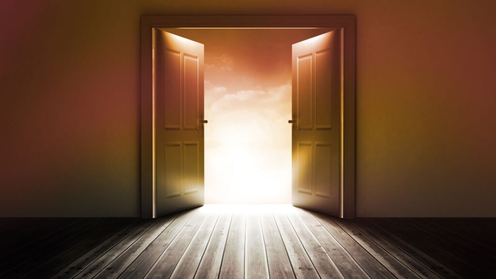 A set of two doors partly open with light shining through the other side.