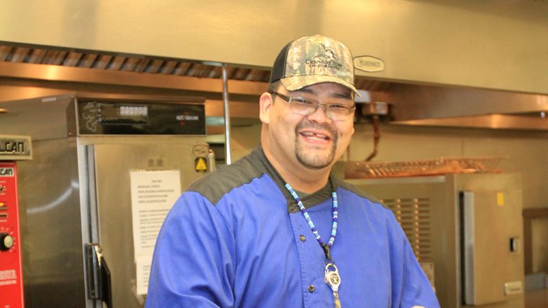 Chef smiling standing in commerical kitchen.