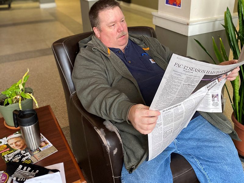 man relaxing and reading newspaper.