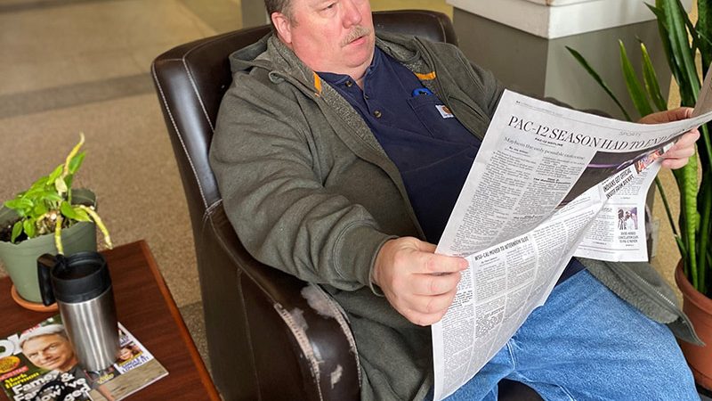 man relaxing and reading newspaper.